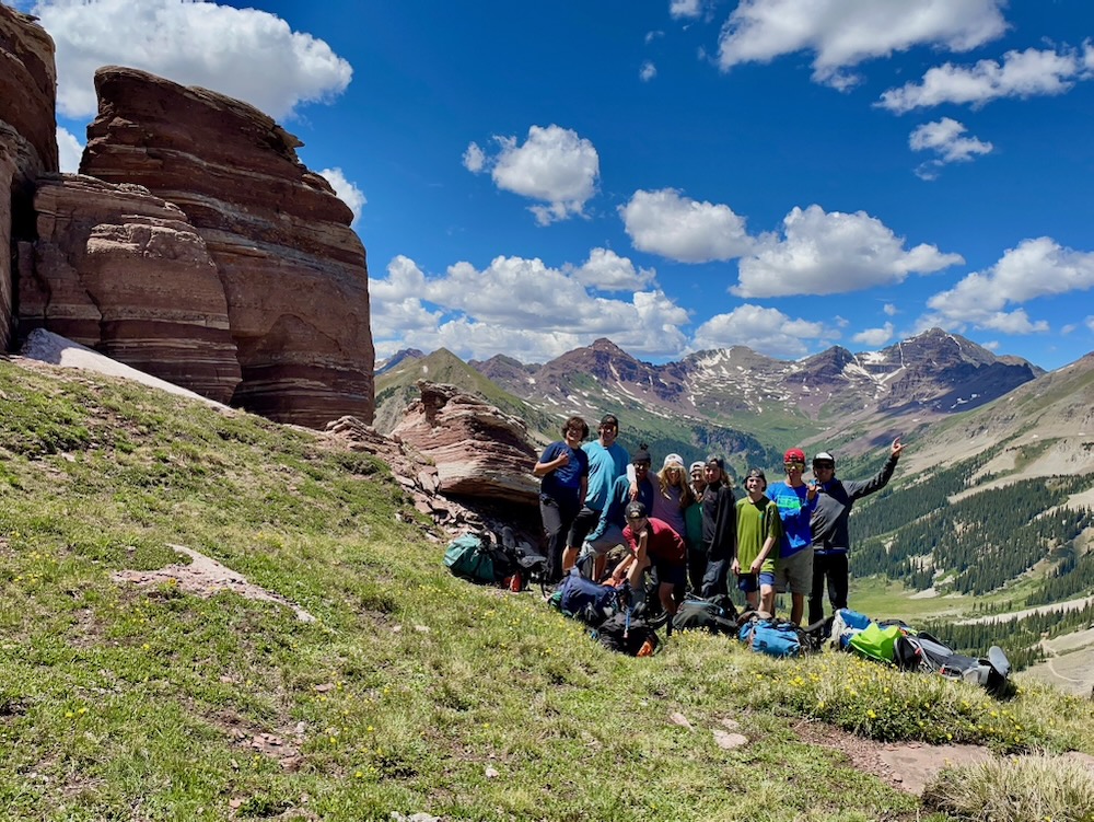 A group of hikers standing next to large striped bouders.